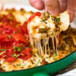 queso fundido in green dish with chip scooping dip