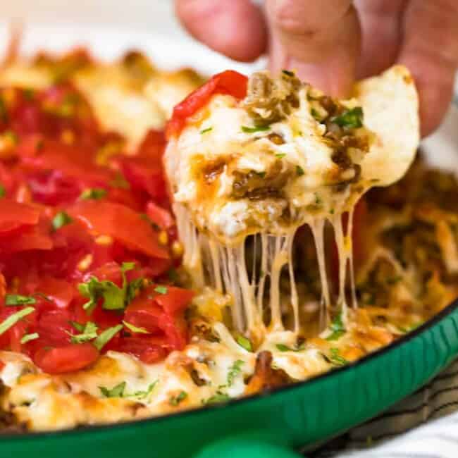 queso fundido in green dish with chip scooping dip