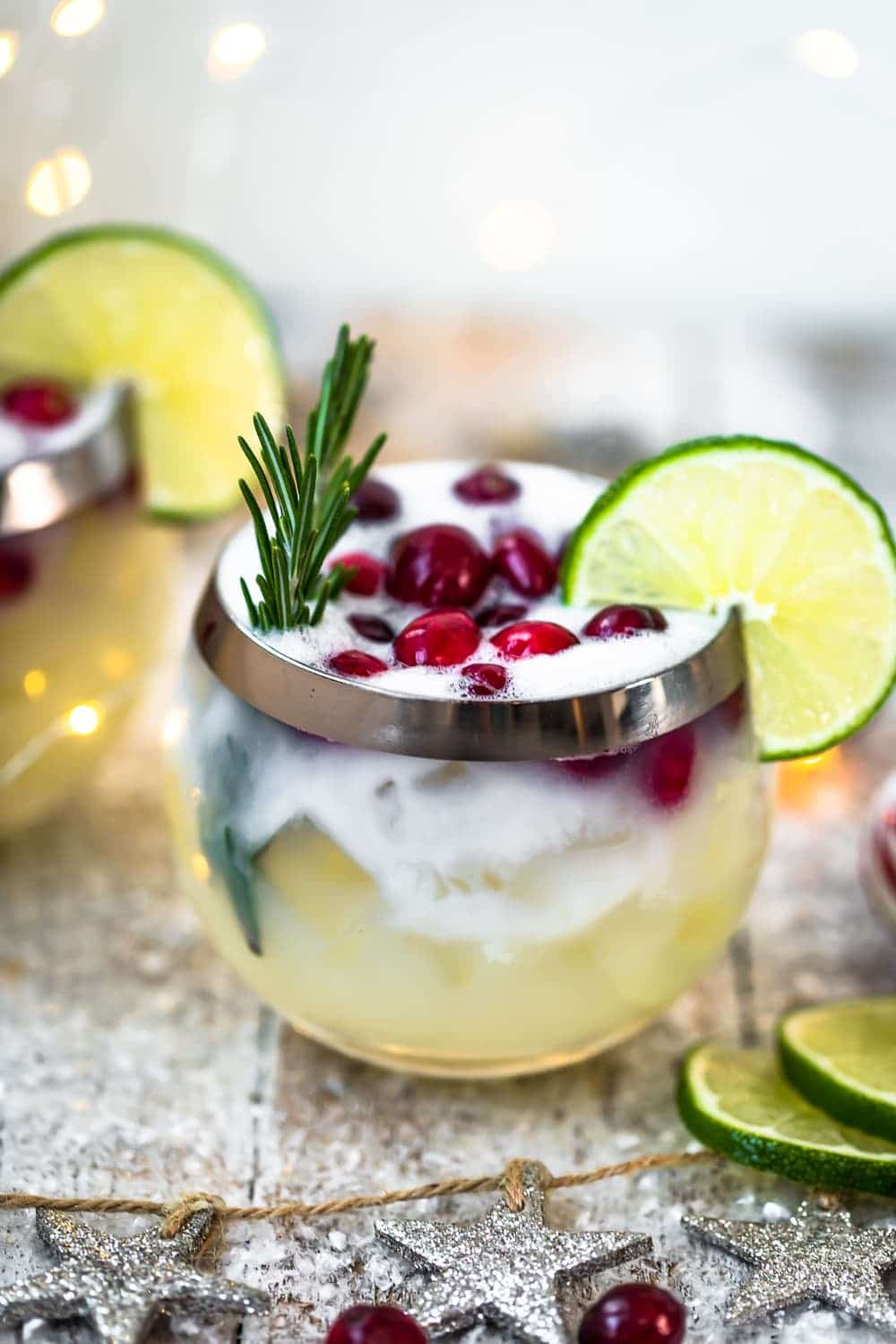 christmas cocktail topped with cranberries, rosemary, and lime