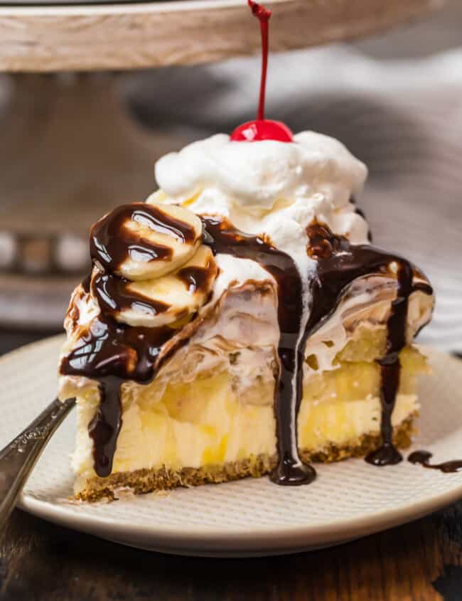 a slice of banana split cake on a plate drizzled in chocolate syrup