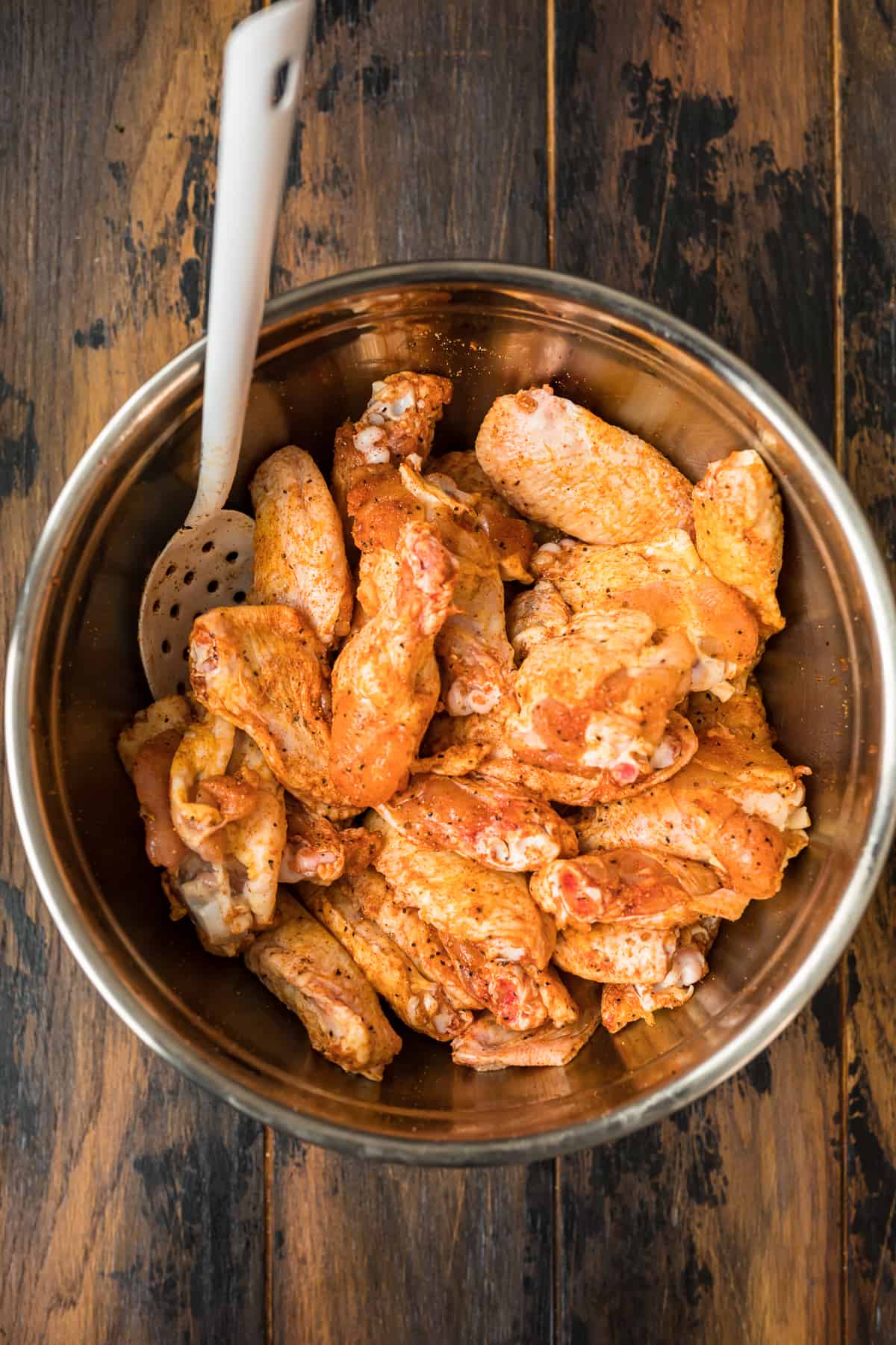 a bowl of chicken wings being stirred with a spoon