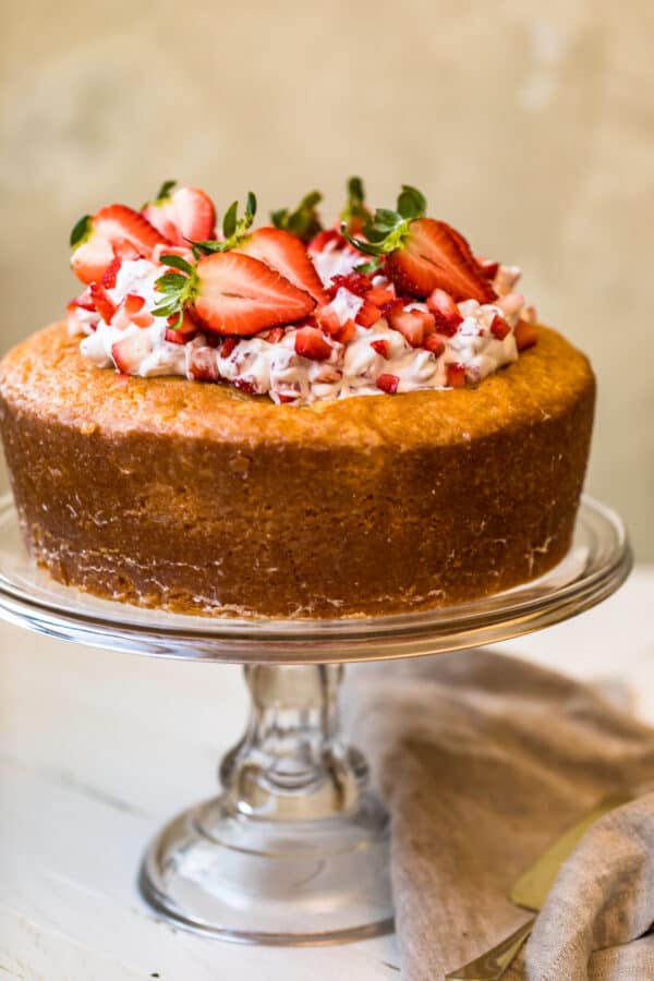 A Kentucky butter cake topped with strawberries and cream on a cake stand