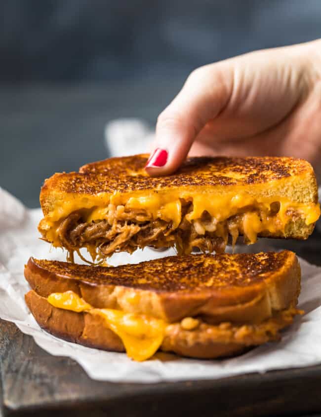 A person holding a delectable pulled pork sandwich.