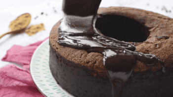 chocolate ganache poured over chocolate bundt cake on a white plate.