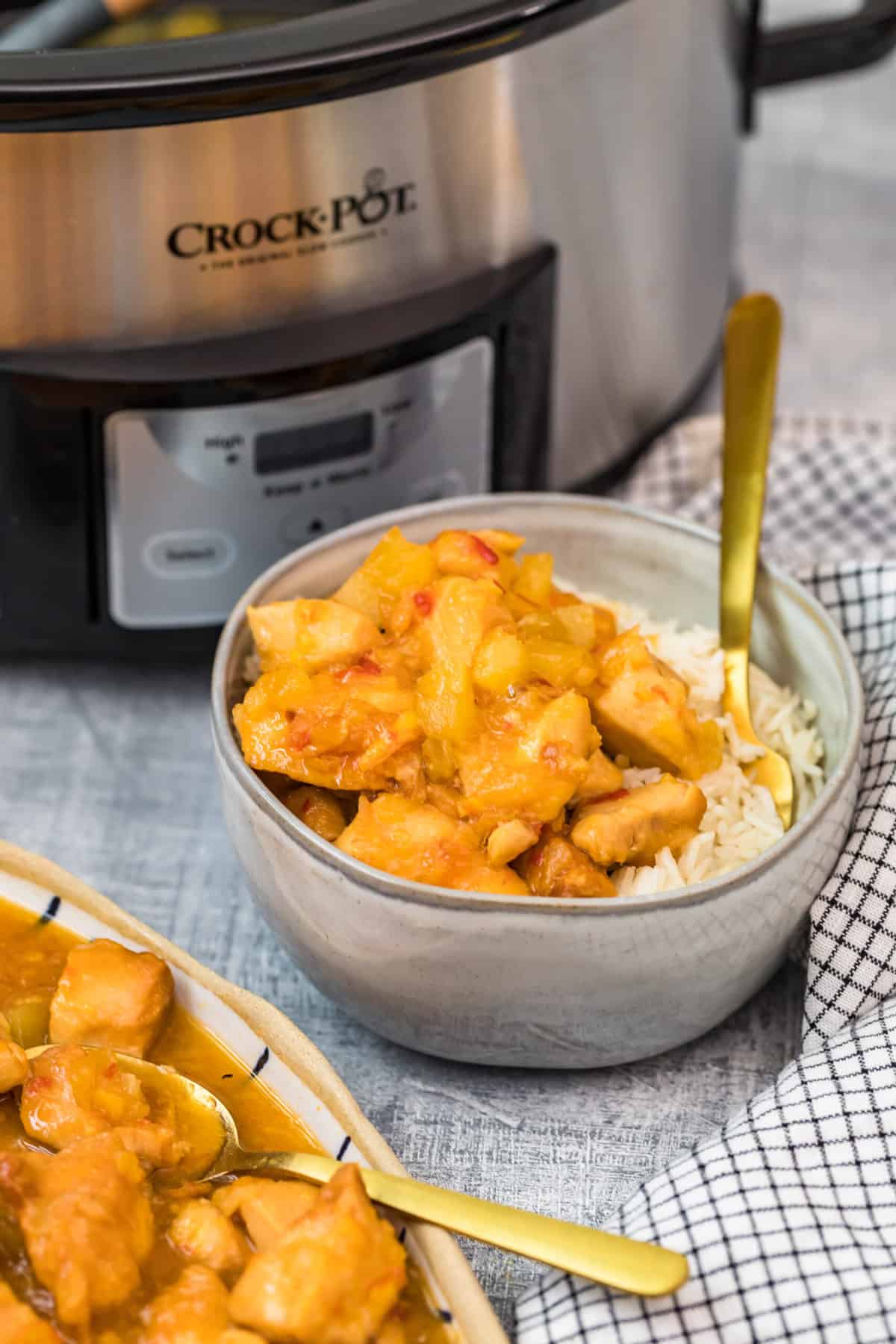 crock pot sweet and sour chicken in a bowl with rice on a table