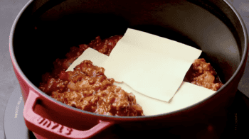 layering meat sauce and lasagna noodles in a dutch oven.