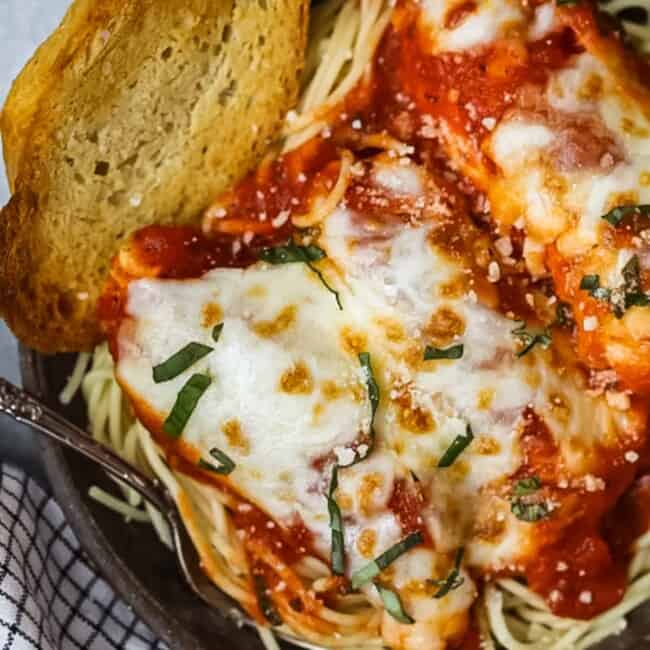 a bowl of chicken parmesan with a slice of bread