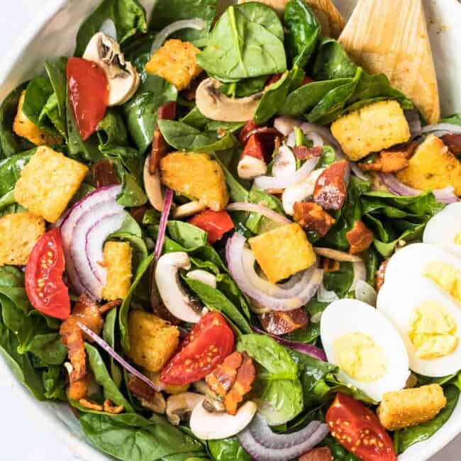 spinach bacon salad with spinach salad dressing in white bowl