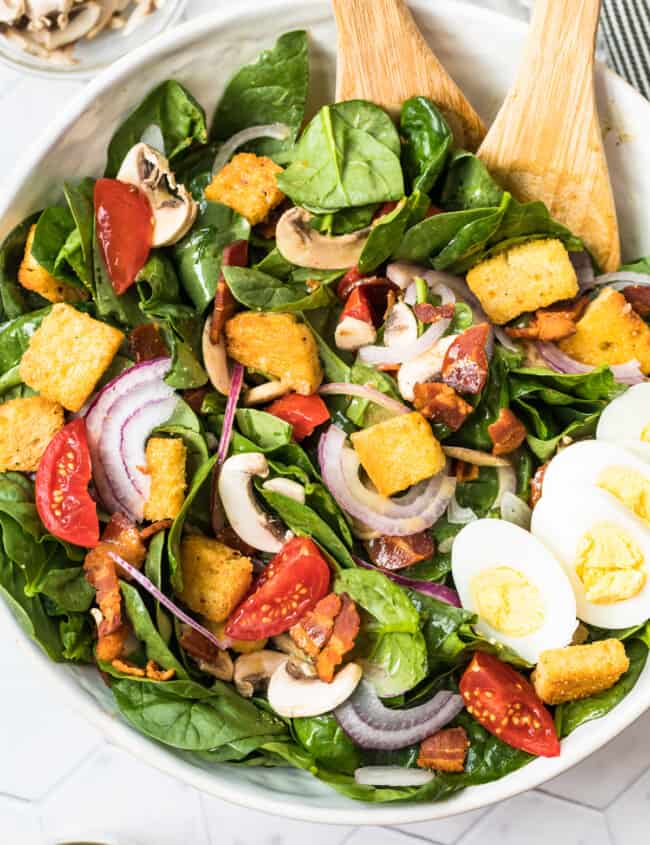 spinach bacon salad with spinach salad dressing in white bowl