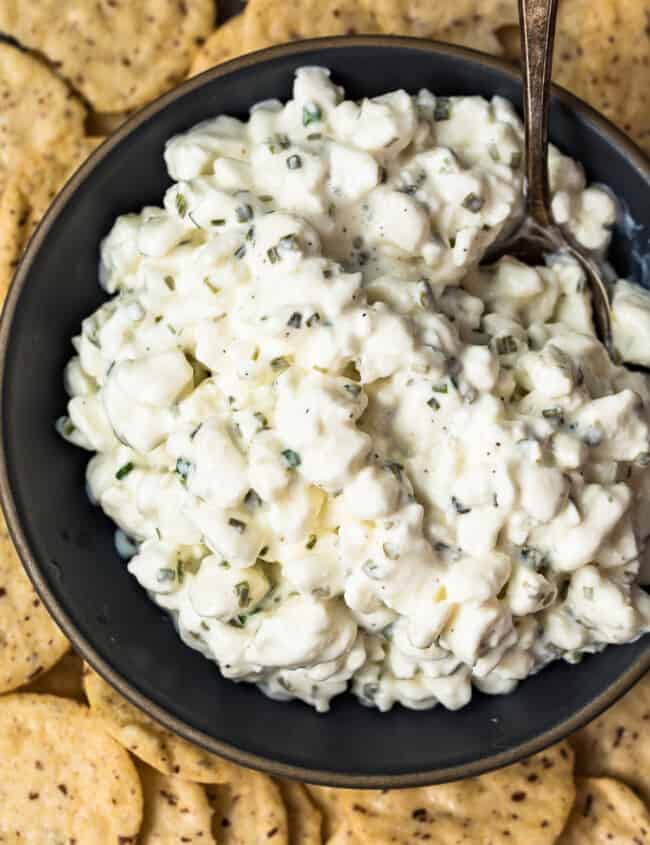 up close image of herbed cottage cheese in bowl surrounded by crackers