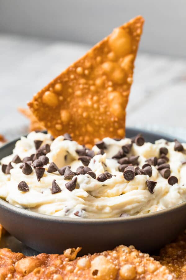 wonton chip dipping in cannoli dip with chocolate chips