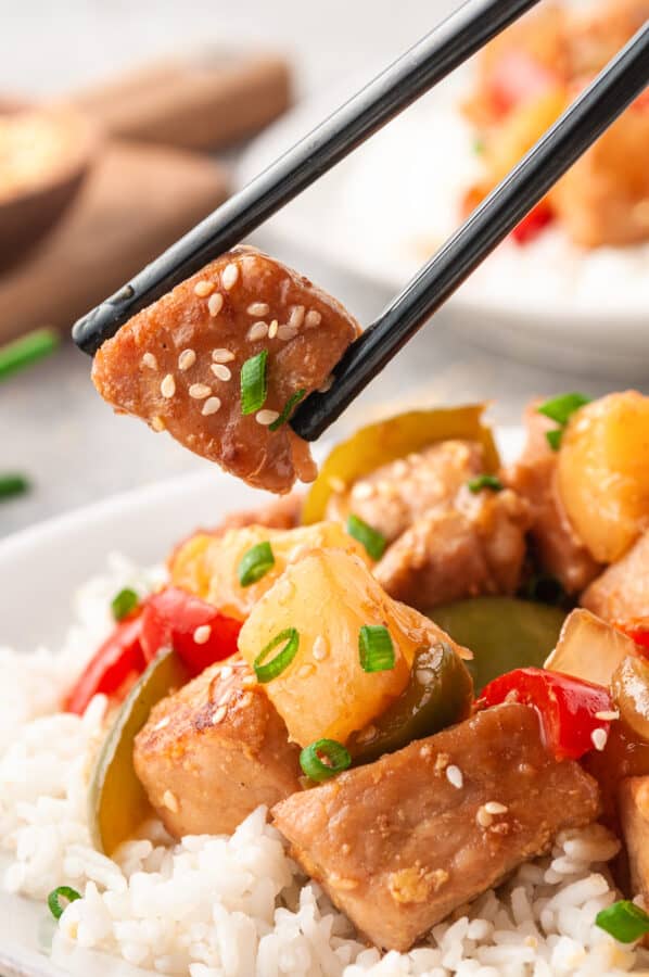 lifting up piece of sweet and sour pork