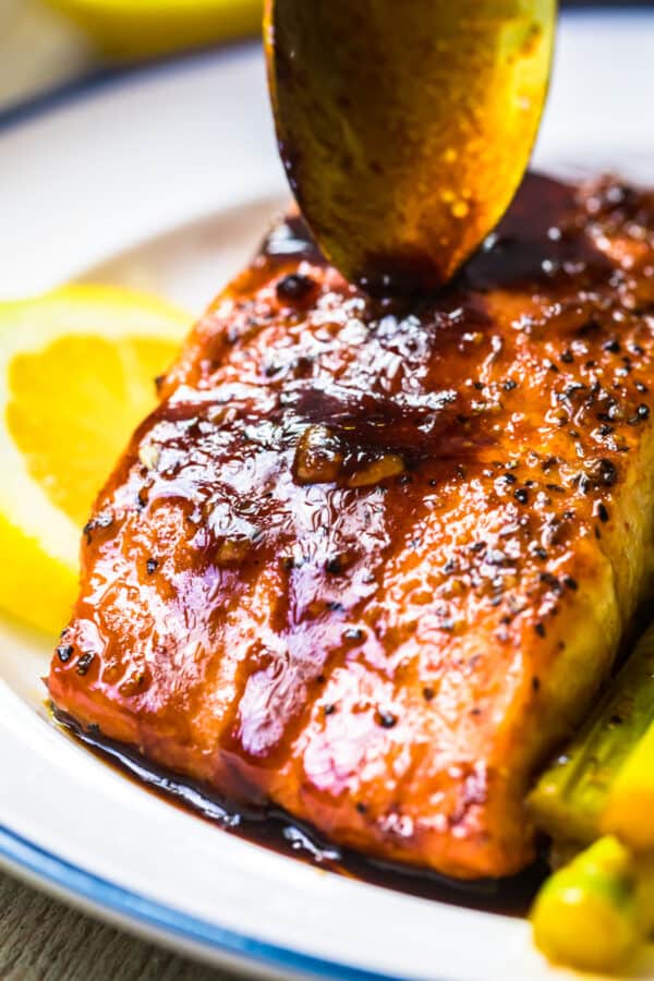 spooning honey garlic sauce over salmon