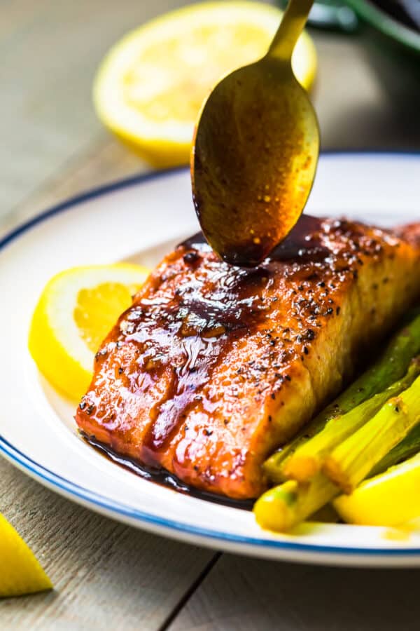 spooning honey garlic sauce over salmon