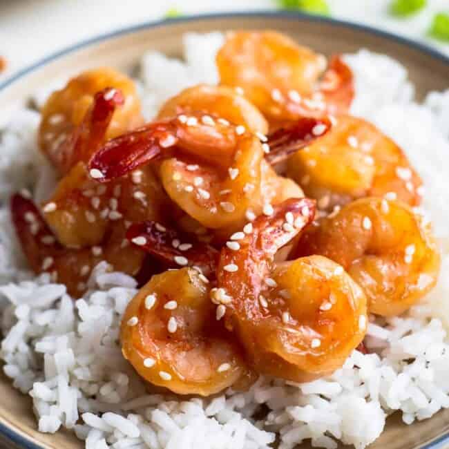 honey sesame shrimp over rice on brown plate