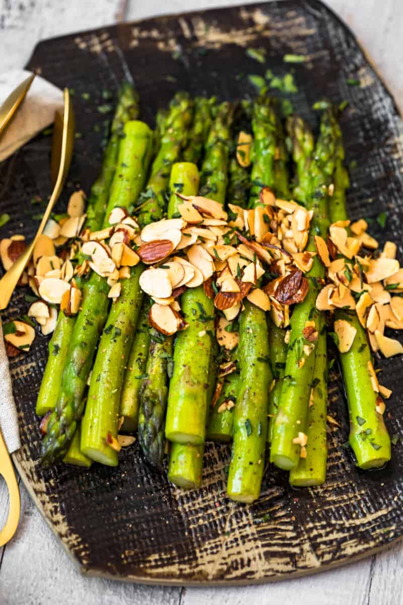 side image of stacked asparagus almondine on platter