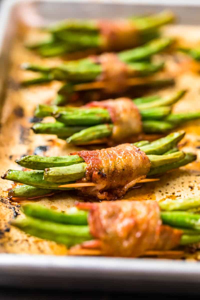 green beans wrapped in bacon on baking sheet