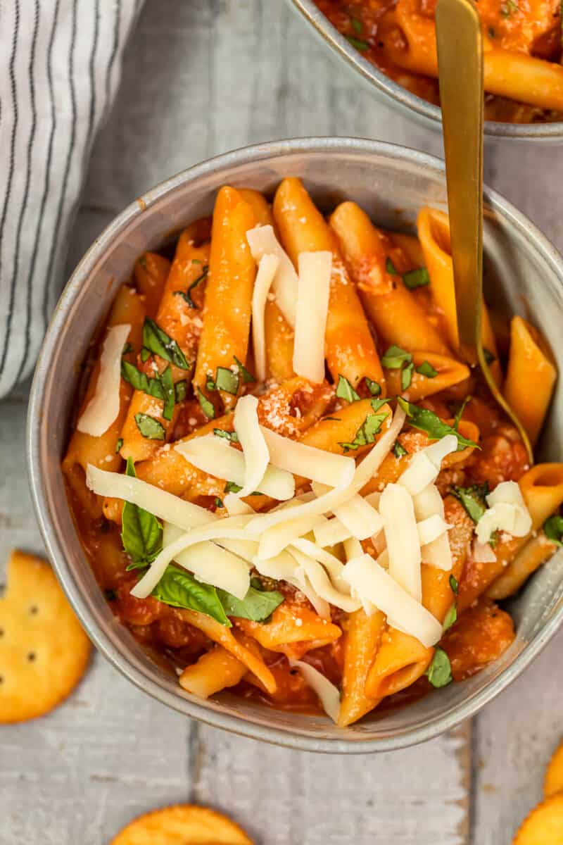 bowl of chicken parmesan soup garnished with cheese and basil