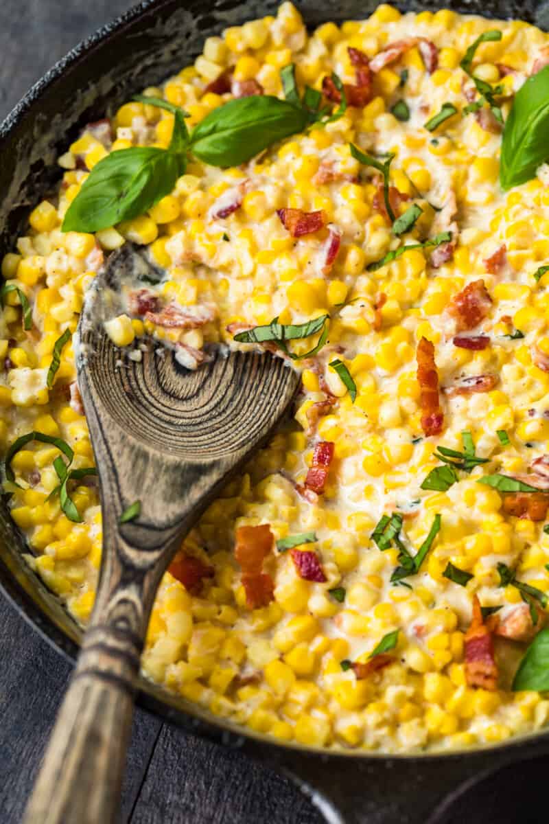 wooden spoon in skillet creamed corn with bacon