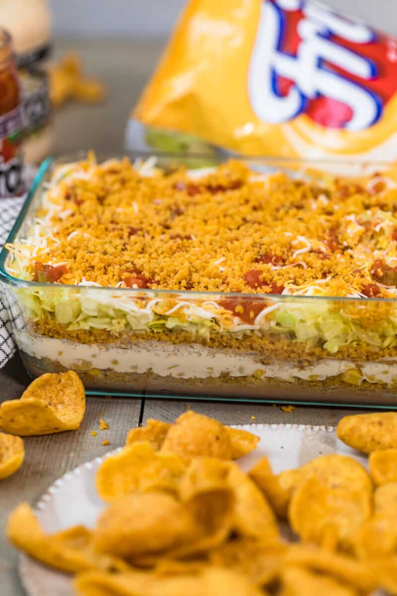 Mexican layer dip with fritos in dish.