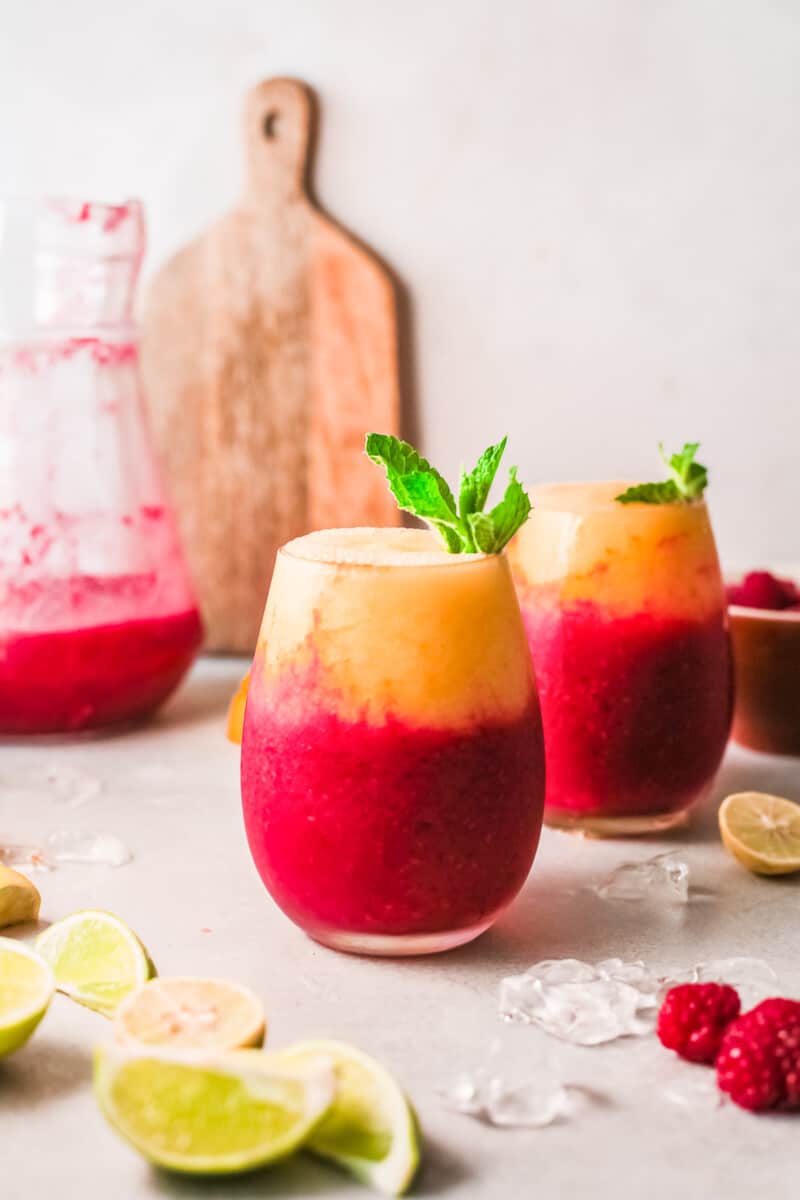 two glasses with layered raspberry mango daiquiris