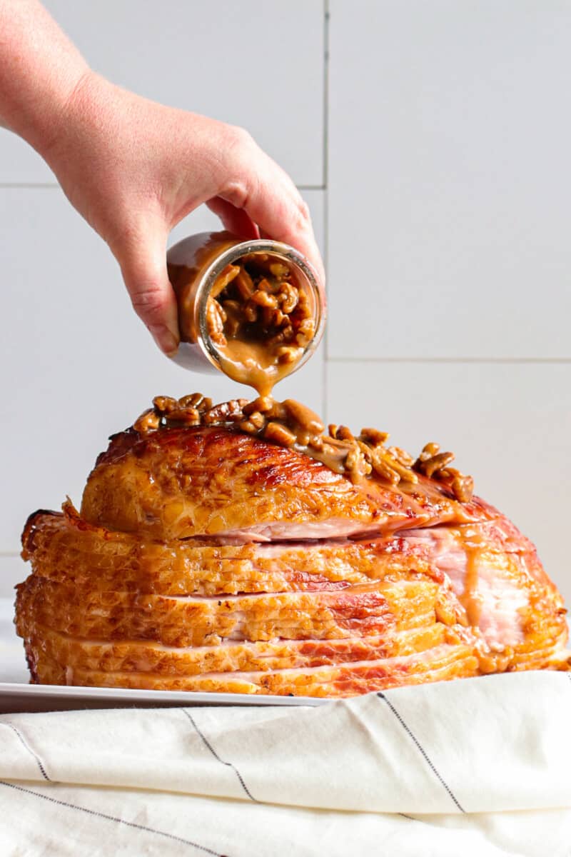 pouring pecan bourbon glaze over spiral ham