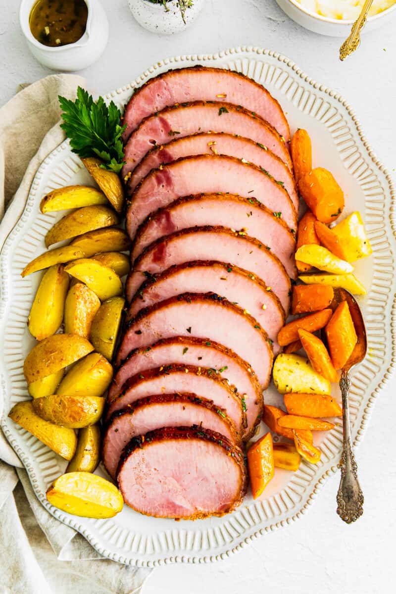 sliced air fryer ham with garlic herb butter on platter