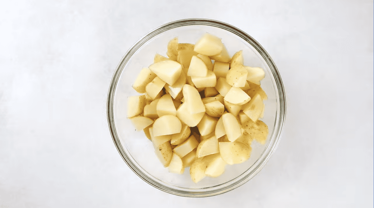 cubed potatoes and olive oil in a glass bowl.