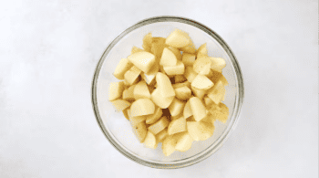 cubed potatoes and olive oil in a glass bowl.