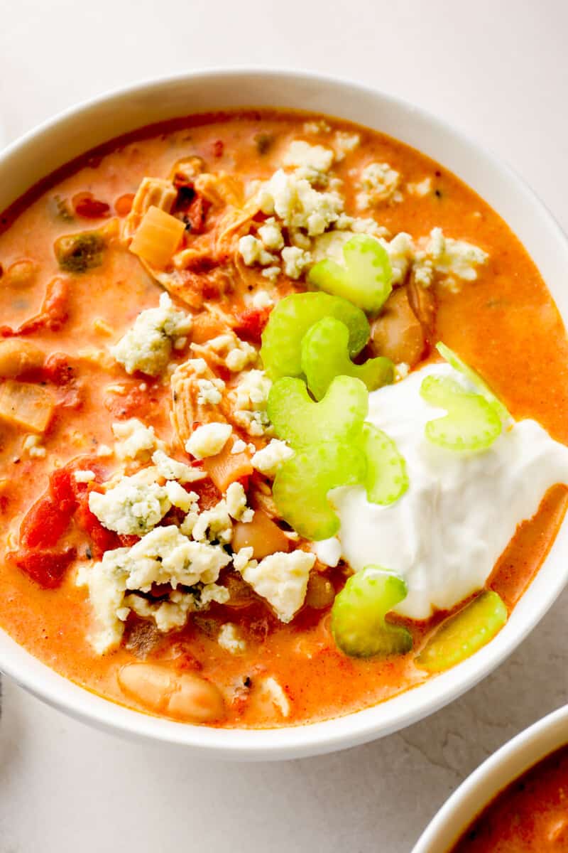 up close buffalo chicken chili in white bowl garnished