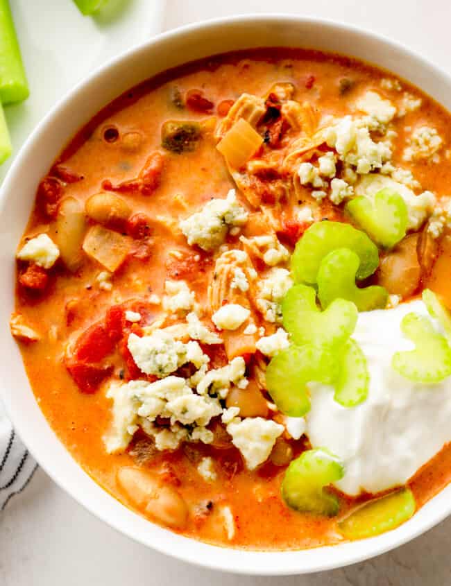 up close buffalo chicken chili garnished with sour cream, blue cheese, and celery