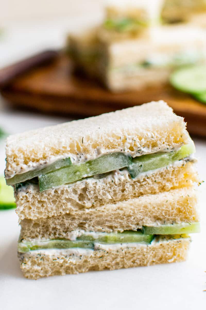 two stacked cucumber sandwiches on white table