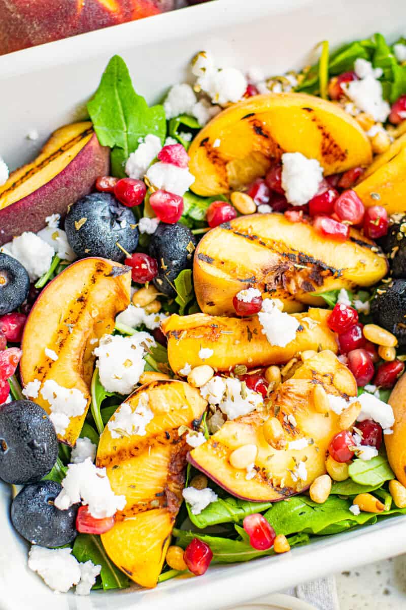 up close grilled peach salad in white serving dish