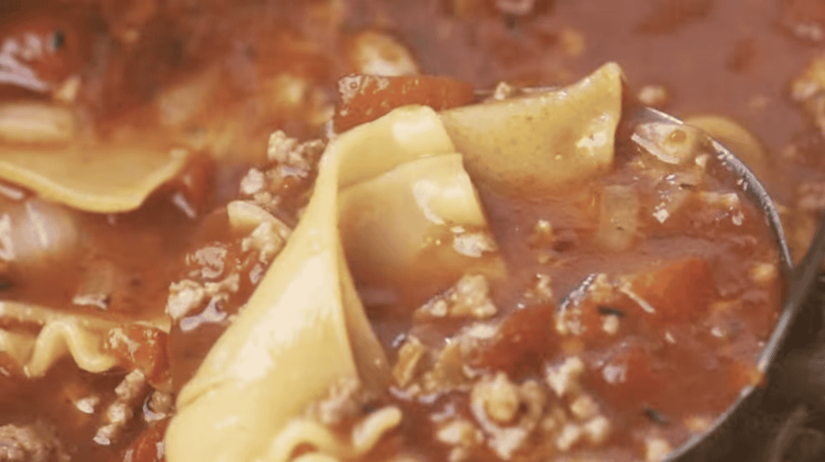 closeup of a ladleful of cooked lasagna soup.