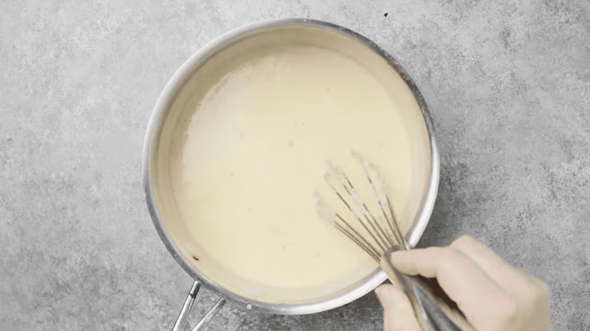 cheese sauce in a pot with a whisk.