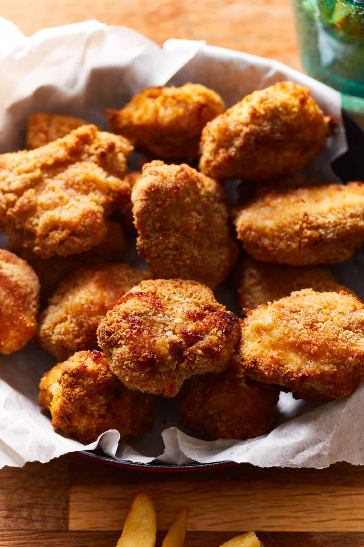 air fryer chicken nuggets in a parchment lined basket.