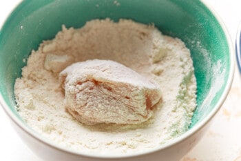 a chicken nugget dunked in flour in a blue bowl.