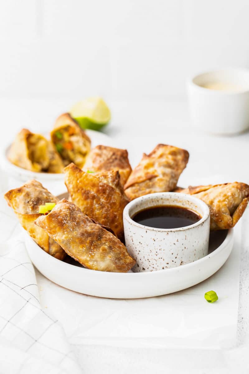 air fryer egg rolls next to bowl of soy sauce