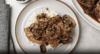 overhead view of chicken marsala over rice on a white plate.