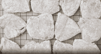 Floured chicken cutlets on a wire rack.