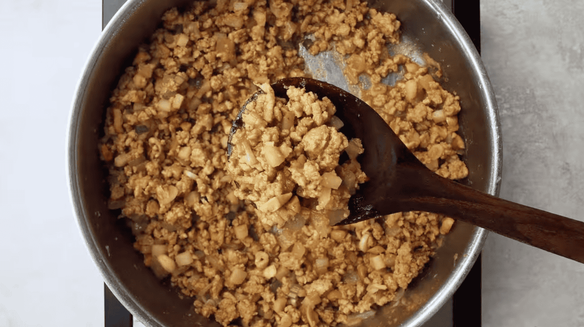 holding up a spoonful of seasoned ground chicken.