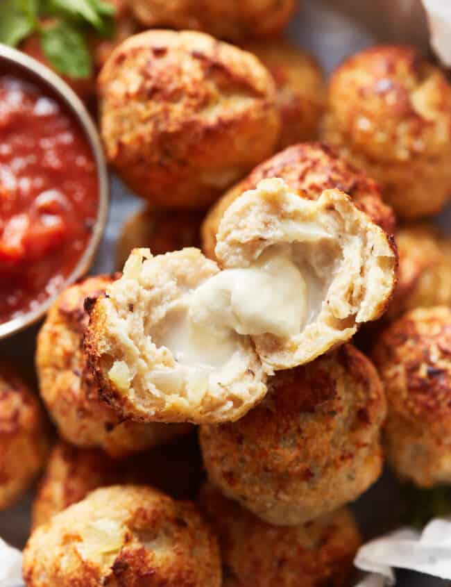 a halved baked turkey meatball on top of a pile of meatballs.