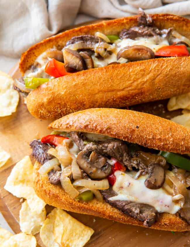 two philly cheesesteaks on cutting board