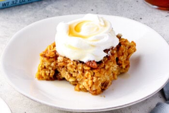 slice of pumpkin pie baked oatmeal with whipped cream and maple syrup.