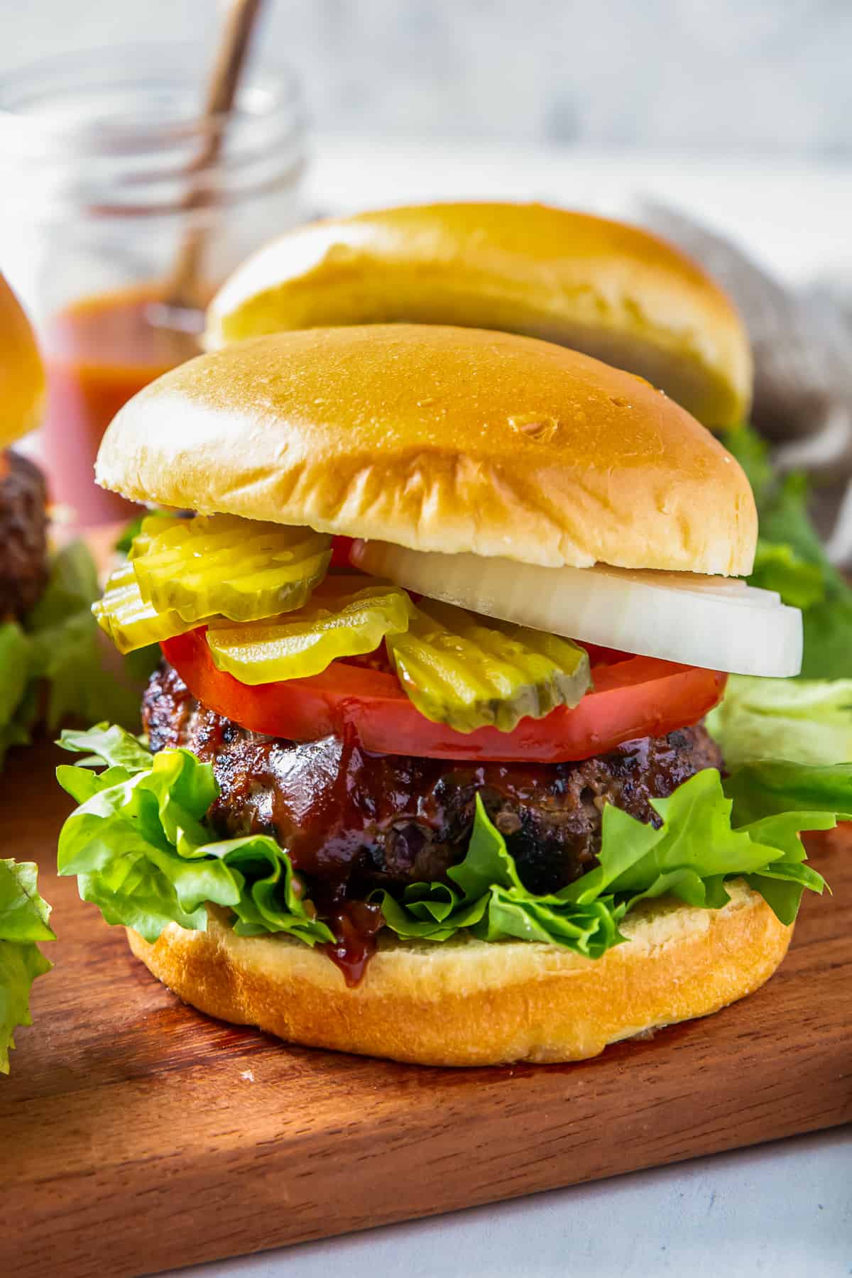 up close grilled bbq burgers with lettuce, tomato, onion, and pickles