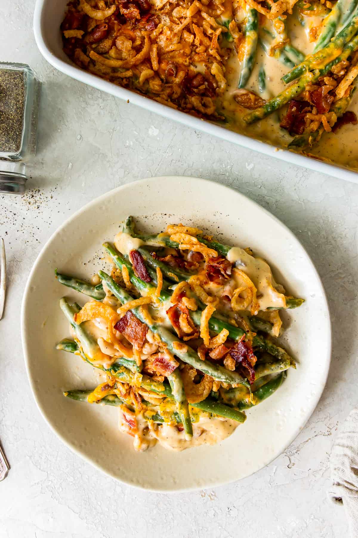 a serving of cheesy green beans with bacon and fried onions on a plate.