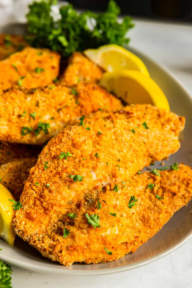 breaded tilapia filets on a platter with lemon slices