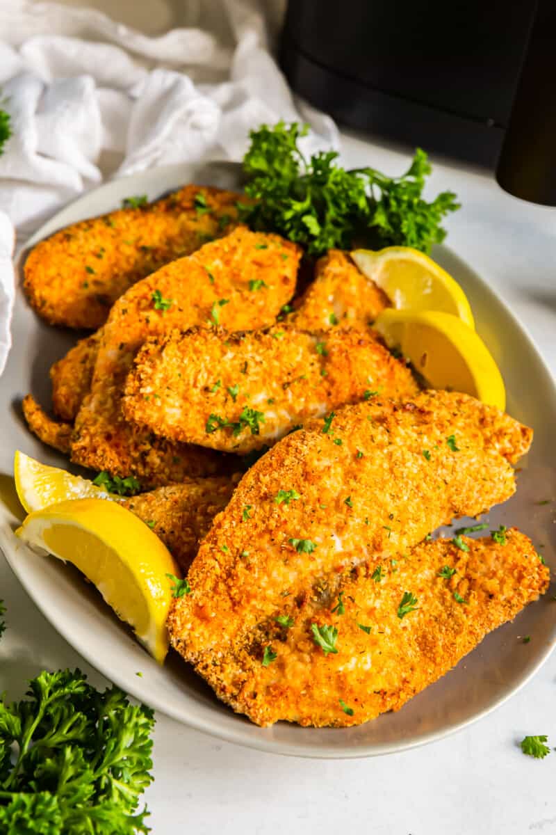 breaded tilapia filets on a platter with lemon slices