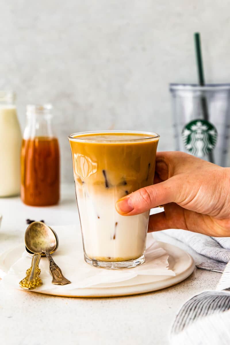 hand holding an apple crisp macchiato in a clear glass