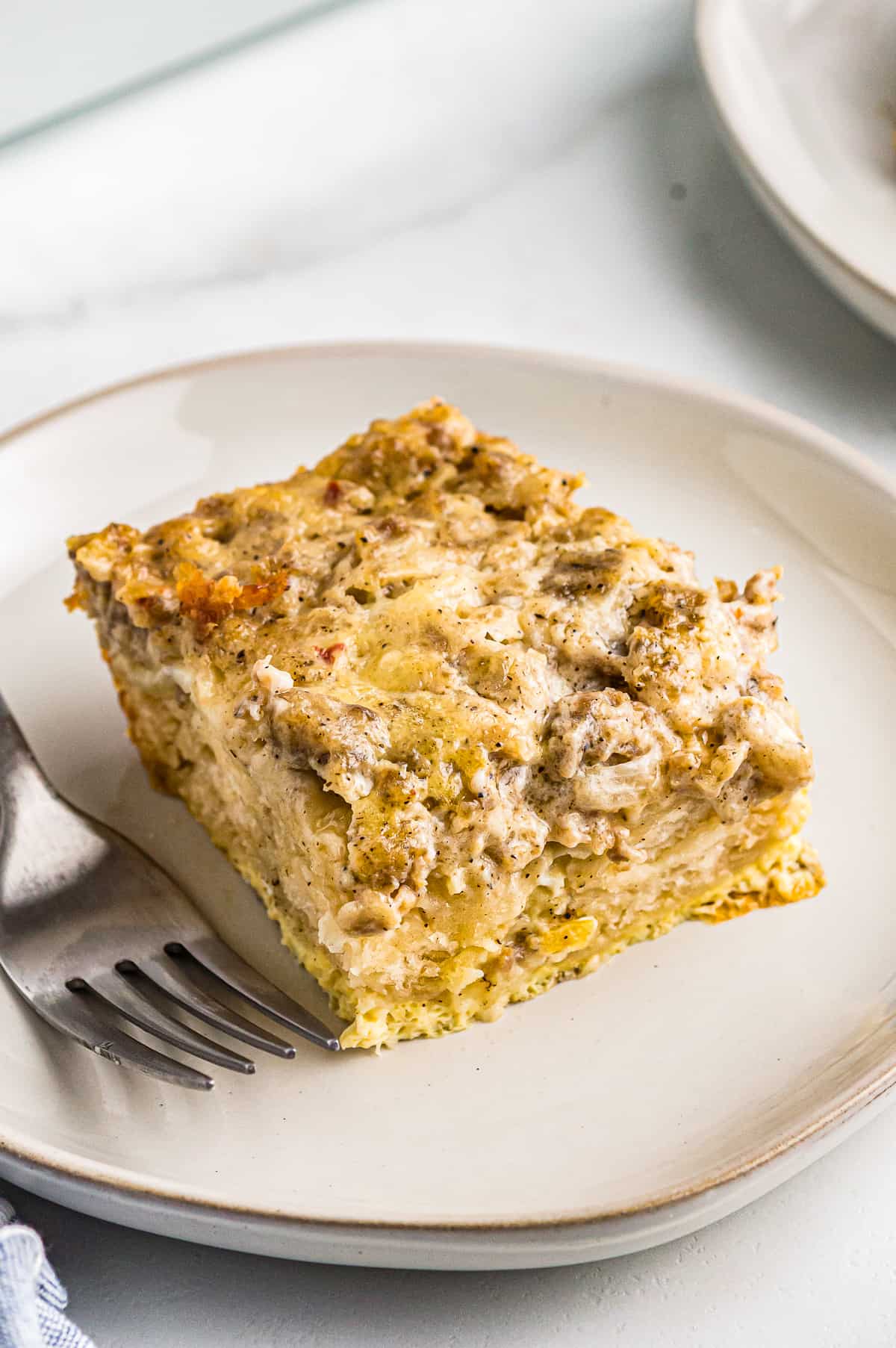 slice of biscuits and gravy casserole on a white plate with a fork